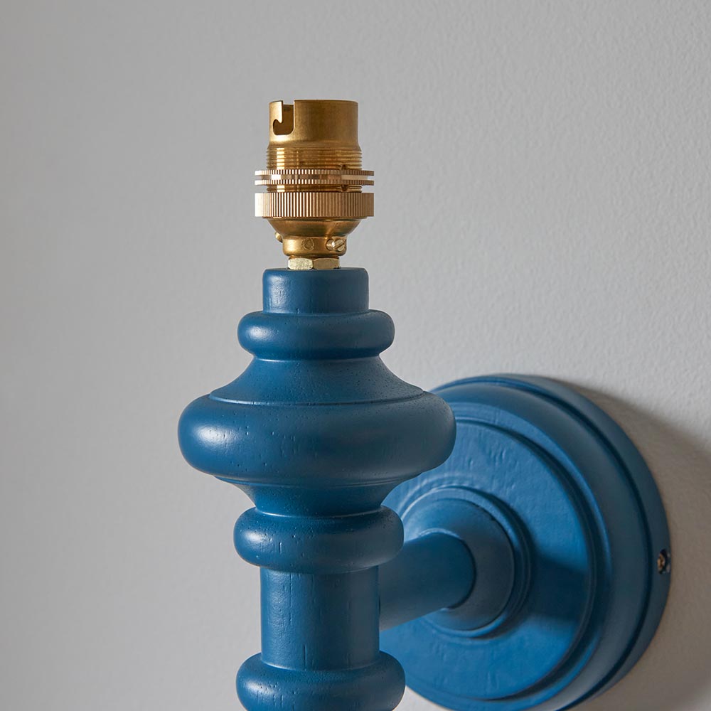 Endon Bevbury Ripple wall light close-up showing the marlin blue turned wooden spindle, brass B22 lamp holder and matching blue circular wall plate.