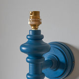 Endon Bevbury Ripple wall light close-up showing the marlin blue turned wooden spindle, brass B22 lamp holder and matching blue circular wall plate.