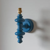 Endon Bevbury Ikat wall light with a satin blue turned wooden spindle and brass B22 lamp holder, shown without shade against a light wall.