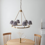 Endon Bevford Zigzag six-light hoop pendant in aged brass with pleated grey zigzag fabric shades, above a wooden dining table and chairs.