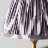 Close-up of an Endon Bevford Zigzag pendant shade in pleated pearl grey faux silk with a zigzag print and taped edge, on an aged brass fitting.