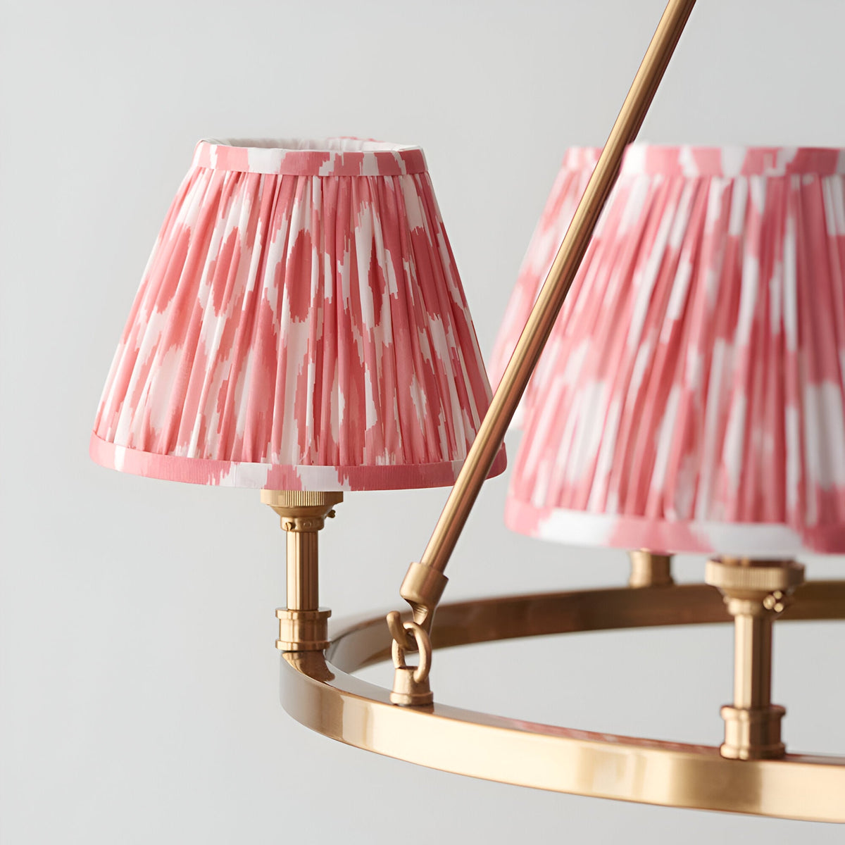 Close-up of the Bevford Ikat 6 Light Pendant in coral, showing pleated fabric shades on an aged brass hoop frame against a plain background.