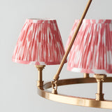 Close-up of the Bevford Ikat 6 Light Pendant in coral, showing pleated fabric shades on an aged brass hoop frame against a plain background.