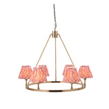Bevford Ikat 6-light hoop pendant with tapered coral pink pleated fabric shades on an antique brass circular frame, shown on a white background.