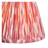 Close-up of a Bevford Ikat 6 Light Pendant shade in coral pink, showing pleated fabric, Ikat print, and taped edge detail against a white background.