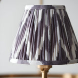 Close-up of the Bevford Zigzag 3 Light Pendant's tapered fabric shade in pleated grey and white zigzag print with taped edges, set on a brass fitting.