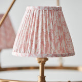 Close-up of an Endon Bevford pendant shade in pleated peach-pink patterned fabric with taped edge, mounted on an aged brass fitting.