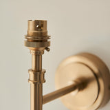 Close-up of Endon Bevford wall light's aged brass B22 lamp holder and stem, with the round wall plate softly blurred behind.