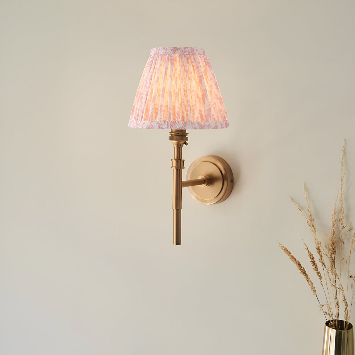 Bevford Leaf Wall Light in aged brass finish with a pleated tapered pink leaf-patterned fabric shade, shown against a plain light background.