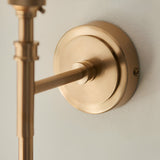 Close-up of the Bevford Leaf Wall Light's brass wall mount and arm, showing the round backplate, screw fixing, and knurled detailing against a plain light wall.