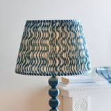 Endon Brenleigh floor lamp with pleated blue Ripple print faux linen shade on a stacked marlin blue metal sphere base, beside a white mantel.