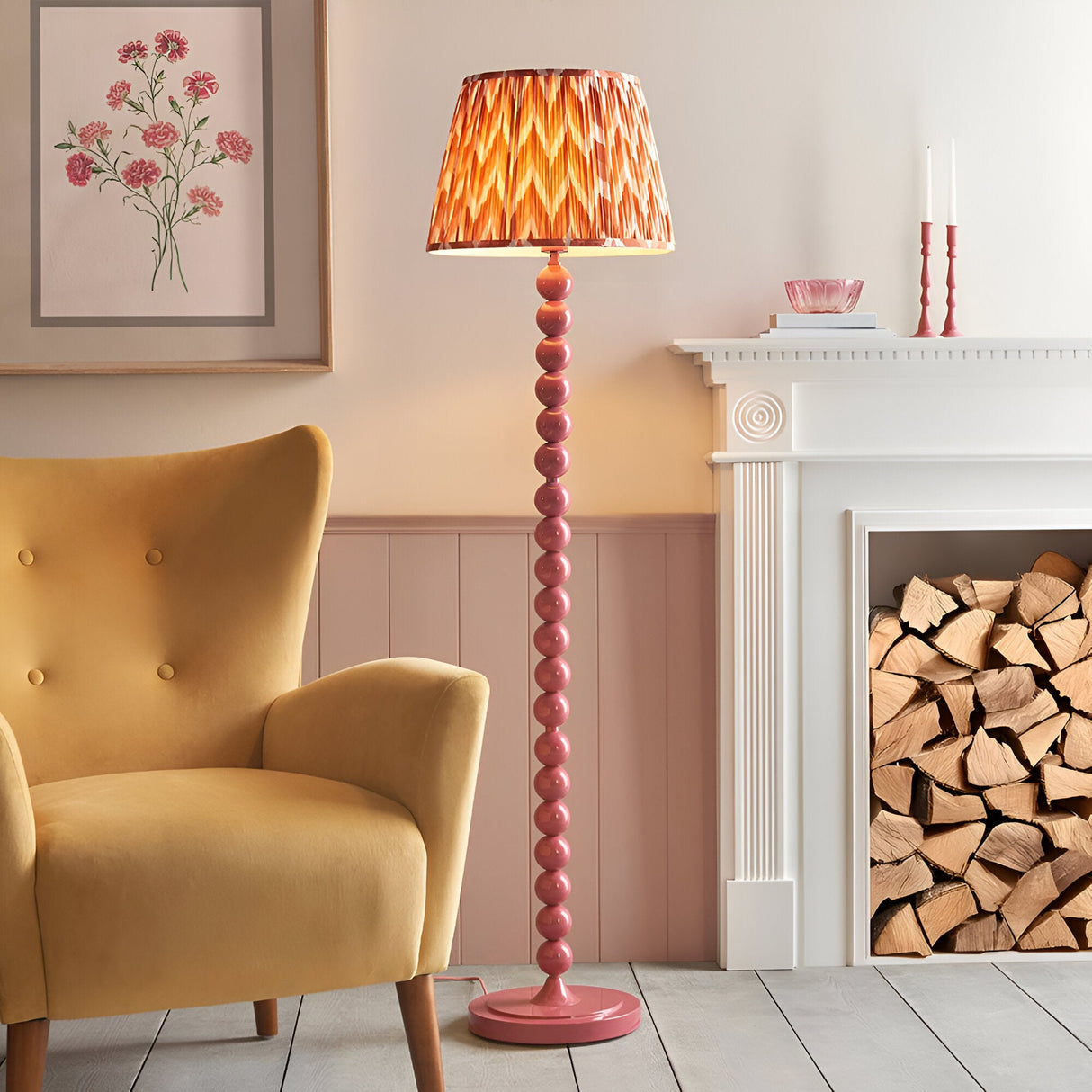 Brenleigh Zigzag Floor Lamp in Pink with stacked spherical metal column base and pleated apricot orange zigzag fabric shade, shown beside a mustard armchair.