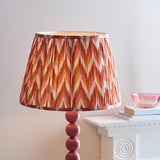 Brenleigh Zigzag Floor Lamp with stacked gloss pink sphere base and pleated apricot orange zigzag shade, shown beside a white mantel.
