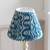 Endon Brenleigh Ripple table lamp with a pleated white and blue wavy-print fabric shade on a gloss white stacked-sphere base.