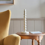 Endon Brenleigh Ripple table lamp base with white stacked-sphere gloss metal design on a wooden side table beside a yellow velvet armchair.