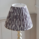 Brenleigh Ikat table lamp with pleated grey and white patterned fabric shade on a white stacked-sphere base, shown against a light neutral background.