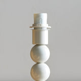 Brenleigh Ikat table lamp base close-up showing white gloss stacked-sphere metal stem with E14 fitting, on a plain light grey background.