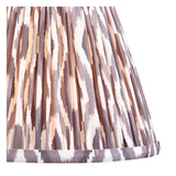 Close-up of the Brenleigh Ikat Table Lamp's pleated 25cm shade in white, grey and brown Ikat-print faux silk with a folded trim edge.