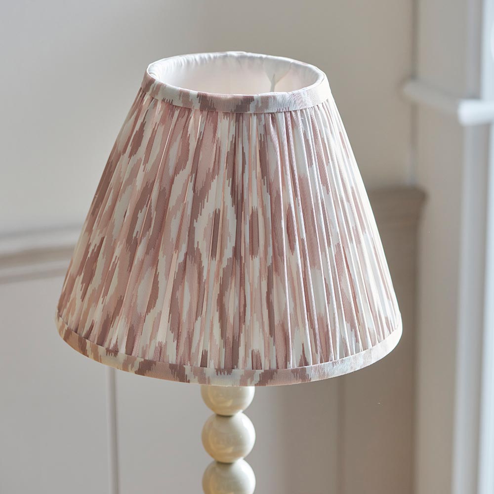 Brenleigh Ikat table lamp with pleated pink-and-white patterned fabric shade on a white stacked-sphere base, set against a neutral background.
