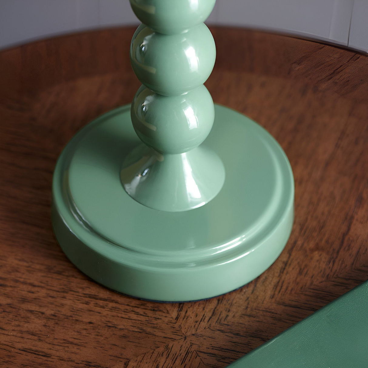 Close-up of the Endon Brenleigh Ripple table lamp base, showing stacked gloss green spheres on a round tiered foot set on a wooden surface.