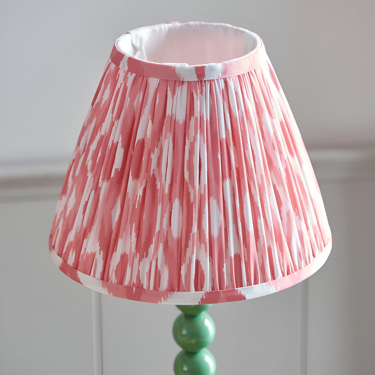 Endon Brenleigh Ikat table lamp with a pleated pink and white ikat faux silk shade on a gloss green stacked-sphere metal base.