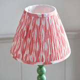 Endon Brenleigh Ikat table lamp with a pleated pink and white ikat faux silk shade on a gloss green stacked-sphere metal base.