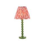 Endon Brenleigh Ikat table lamp with a green stacked-sphere metal base and pink pleated ikat faux silk shade on a white background.