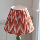 Brenleigh Zigzag Table Lamp with pleated terracotta and white zigzag-print shade on a green gloss stacked-sphere metal base.