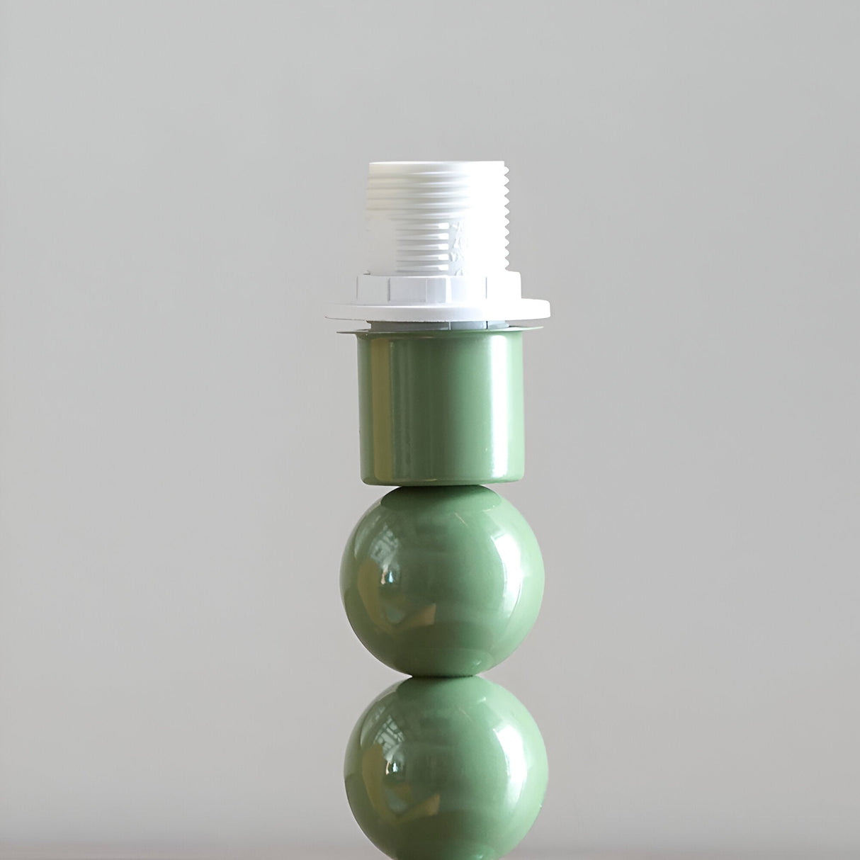 Brenleigh Ivy Table Lamp base close-up showing a stacked-sphere green metal column with white E14 bulb holder, on a plain light background.