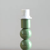 Brenleigh Ivy Table Lamp base close-up showing a stacked-sphere green metal column with white E14 bulb holder, on a plain light background.
