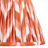 Close-up of the Brenleigh Zigzag Table Lamp's pleated fabric shade in orange and white zigzag pattern, with a rust-toned trim edge.