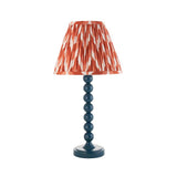 Brenleigh Zigzag table lamp with a blue stacked-sphere metal base and pleated orange and white zigzag-print fabric shade, on a plain white background.