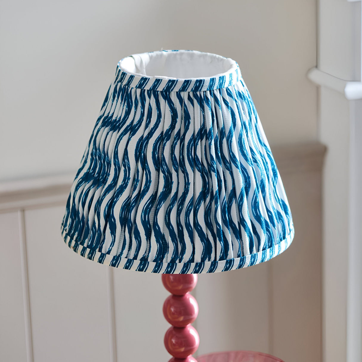 Endon Brenleigh Ripple table lamp with a pleated blue wave-print faux linen shade on a pink gloss stacked-sphere metal base.
