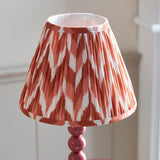 Brenleigh Zigzag Table Lamp in pink, with a pleated chevron-pattern fabric shade on a stacked-sphere gloss metal base, shown against a light background.