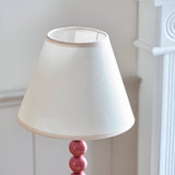 Endon Brenleigh Ivy table lamp close-up showing tapered vintage white cotton-mix shade with almond taped edge above a glossy pink stacked-sphere base.