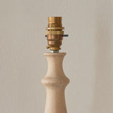 Brenhurst Table Lamp base close-up showing brass B22 bayonet lamp holder atop a natural turned wood stem, against a plain light background.