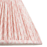 Close-up of the Brenhurst table lamp's pleated shade in pink and white leaf-print faux linen fabric, showing gathered pleats and trim edge.