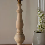 Brenhurst Table Lamp base in vintage white, hand-turned solid wood with a brass switched bulb holder, shown without shade against a plain wall.
