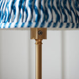 Close-up of the Endon Ashstead LED Ripple Floor Lamp showing the brushed aged brass stem, touch dimmer button, and blue and white pleated shade edge.