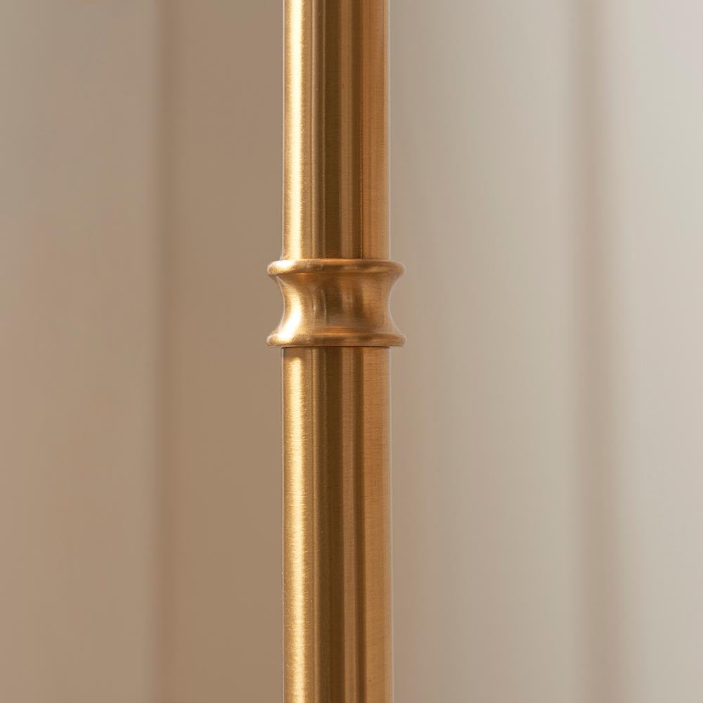 Close-up of the brushed aged brass stem on the Endon Ashstead LED Ripple floor lamp, showing a decorative collar detail against a soft neutral background.