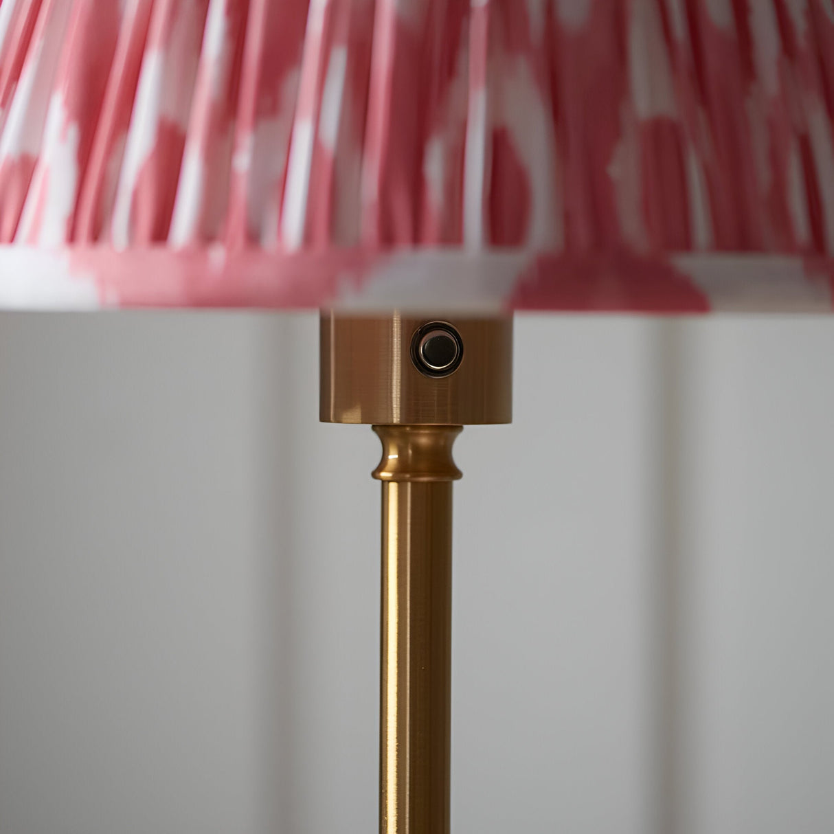 Close-up of Endon Ashstead LED floor lamp showing brushed brass stem, touch dimmer button and pleated coral pink Ikat fabric shade edge.