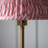 Close-up of the Endon Ashstead LED floor lamp's brushed brass stem and touch dimmer button beneath the pink and white Ripple pleated shade.