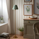 Endon Ashstead LED floor lamp with brushed brass stem and green zigzag pleated shade, styled in a cottage-style room beside a sideboard and window.
