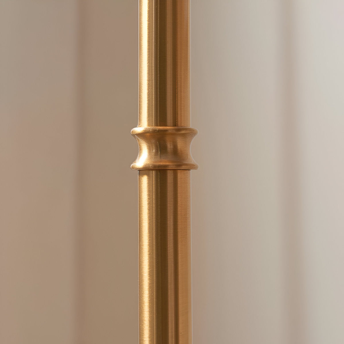Close-up of the brushed aged brass stem on the Endon Ashstead floor lamp, showing a decorative ring detail against a neutral background.