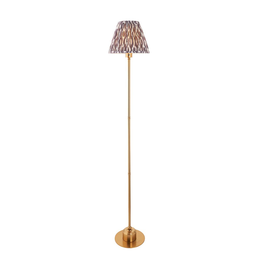Endon Ashstead LED floor lamp with slim brushed brass stem, round base, and pleated Ikat shade in white and grey, on a plain background.