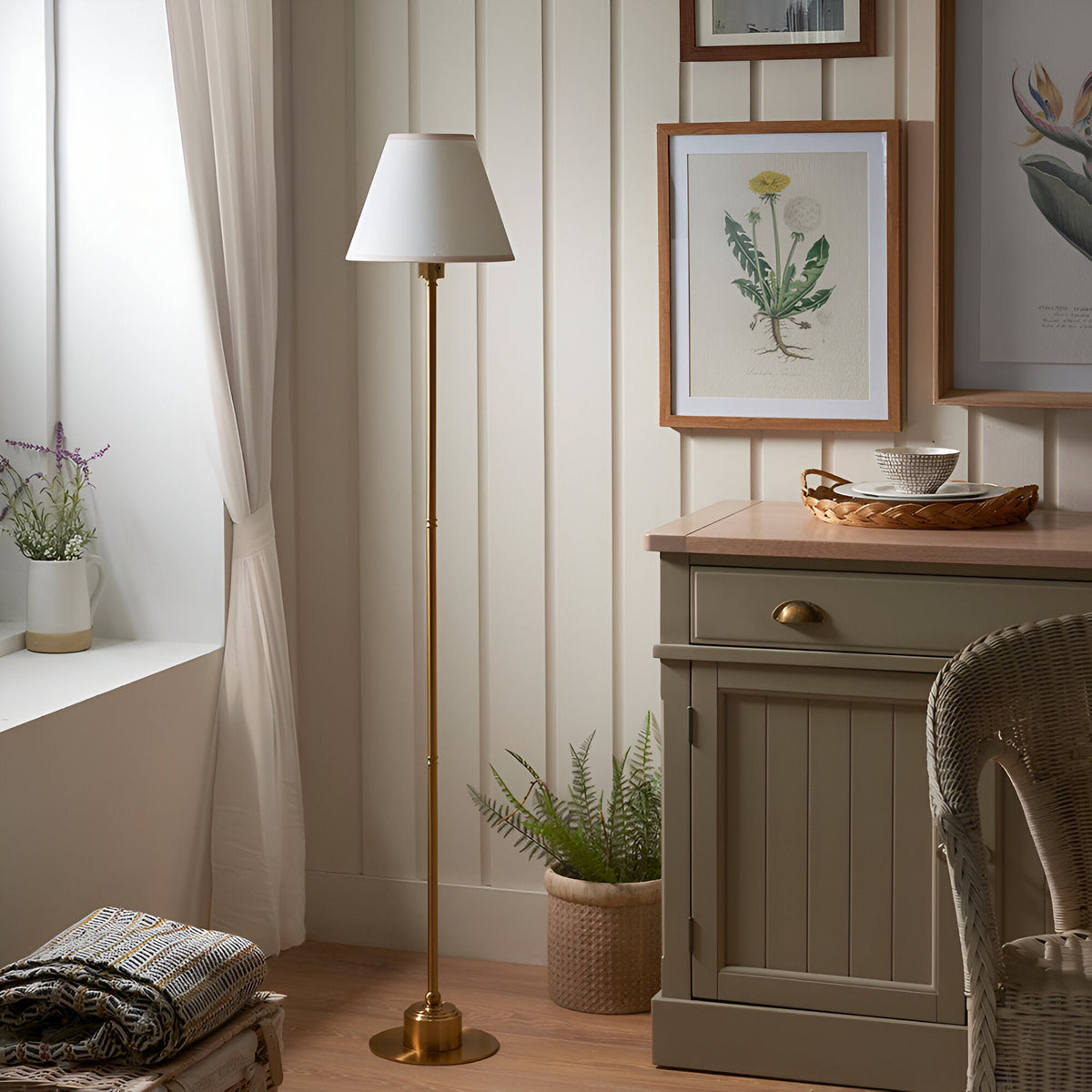 Endon Ashstead LED Ivy floor lamp with vintage white cotton shade and brushed aged brass stem, styled in a cottage corner beside a sideboard and window.