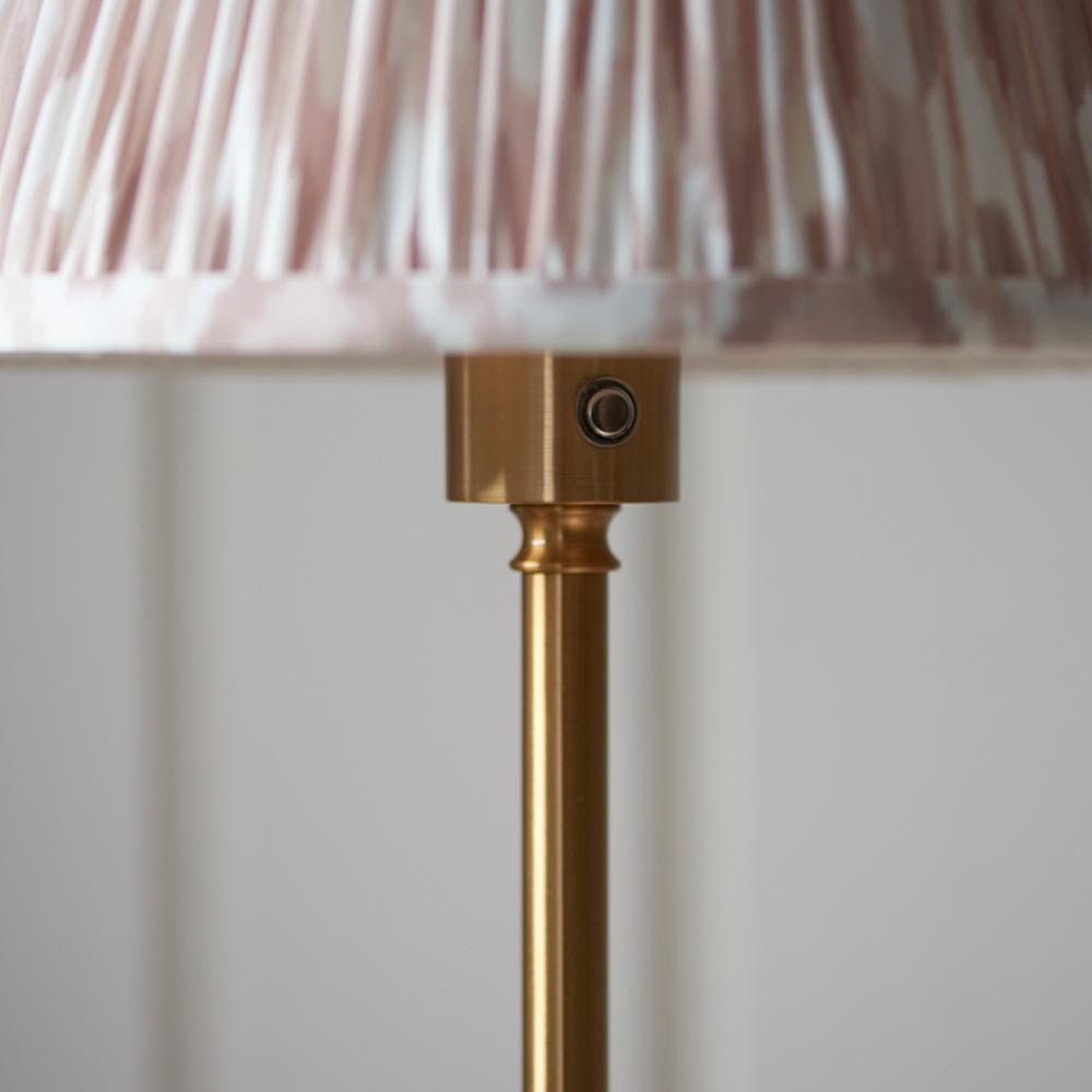 Close-up of the Endon Ashstead LED Ikat Floor Lamp showing the brushed brass stem, touch dimmer button, and pleated pink and white Ikat shade.