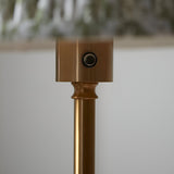 Close-up of the Endon Ashstead floor lamp's brushed aged brass stem, showing the cylindrical top housing with a small touch dimmer button.