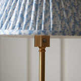 Ashstead LED Leaf Floor Lamp close-up showing brushed aged brass stem, control button, and pleated blue and white leaf-print fabric shade.