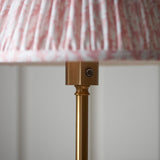 Close-up of the Ashstead LED Leaf Floor Lamp's brushed brass stem and switch beneath a pleated pink and white patterned fabric shade.
